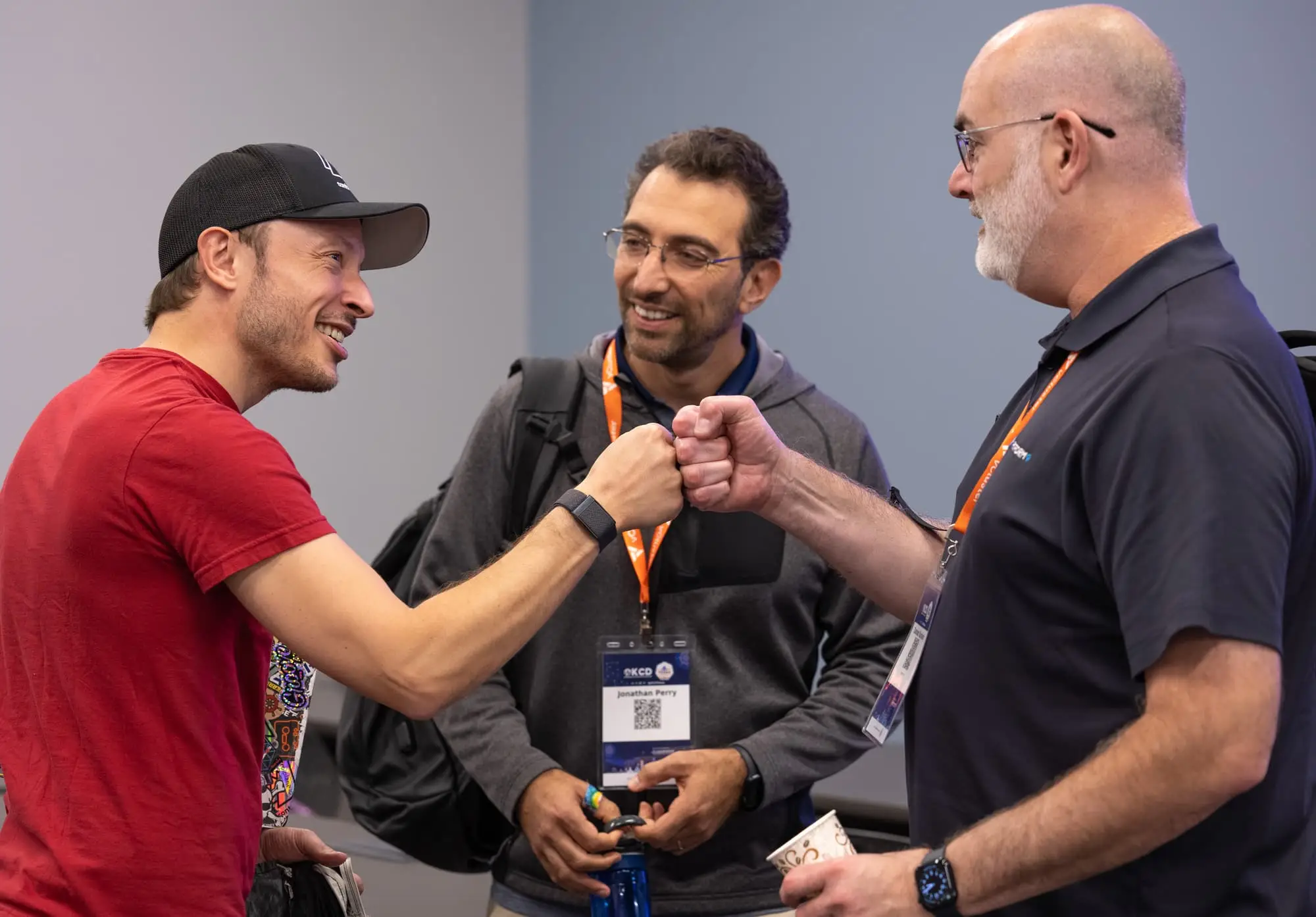 Three attendees bump fists in the hallway between sessions.